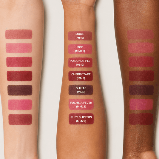 Three forearm swatches display multiple lipstick shades labeled with names and codes, including Moxie, Mod, Poison Apple, Cherry Tart, Shiraz, Fuchsia Fever, and Ruby Slippers, on a light gray background.