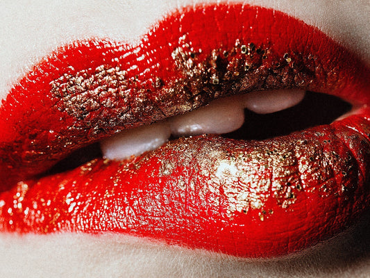 Close-up of lips with red lipstick and gold flakes illustrating how to fix common lip makeup mistakes
