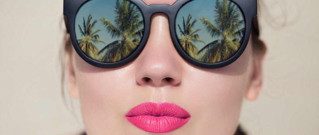 Close-up of woman wearing sunglasses and bright pink heat resistant lip products for summer