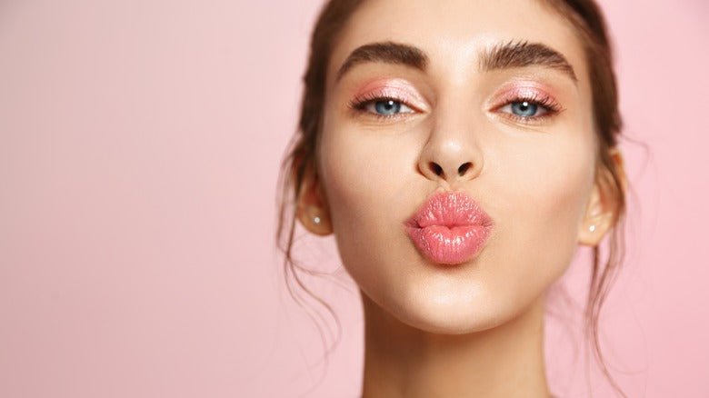 Close up of woman pursing lips with makeup illustrating how to get perfect lips effectively