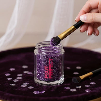 Pout Perfect amethyst glitter lip dust in a clear jar with brush applying purple glitter dust