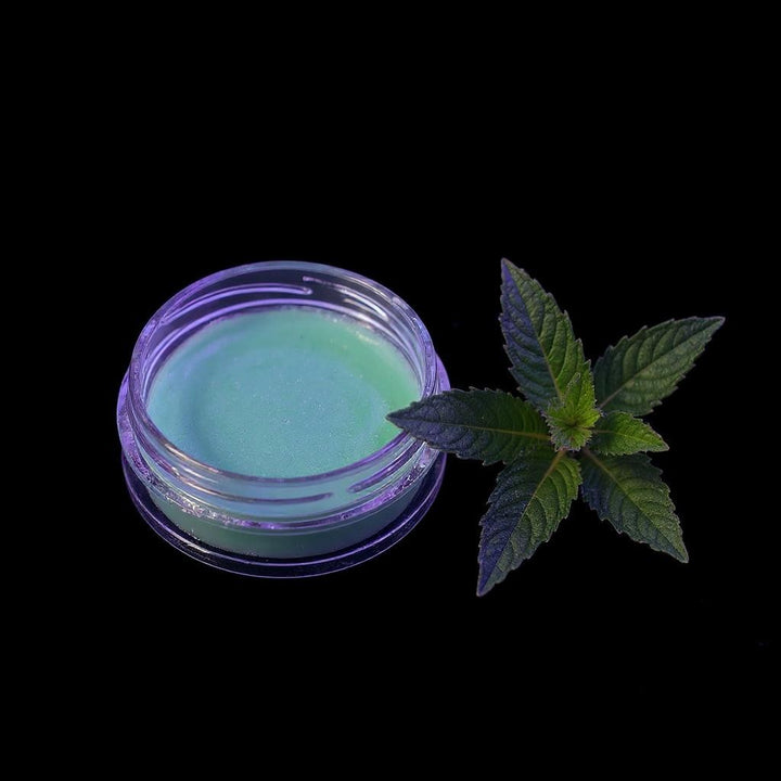 Pout Perfect sugar mint lip scrub in clear jar beside fresh green mint leaves